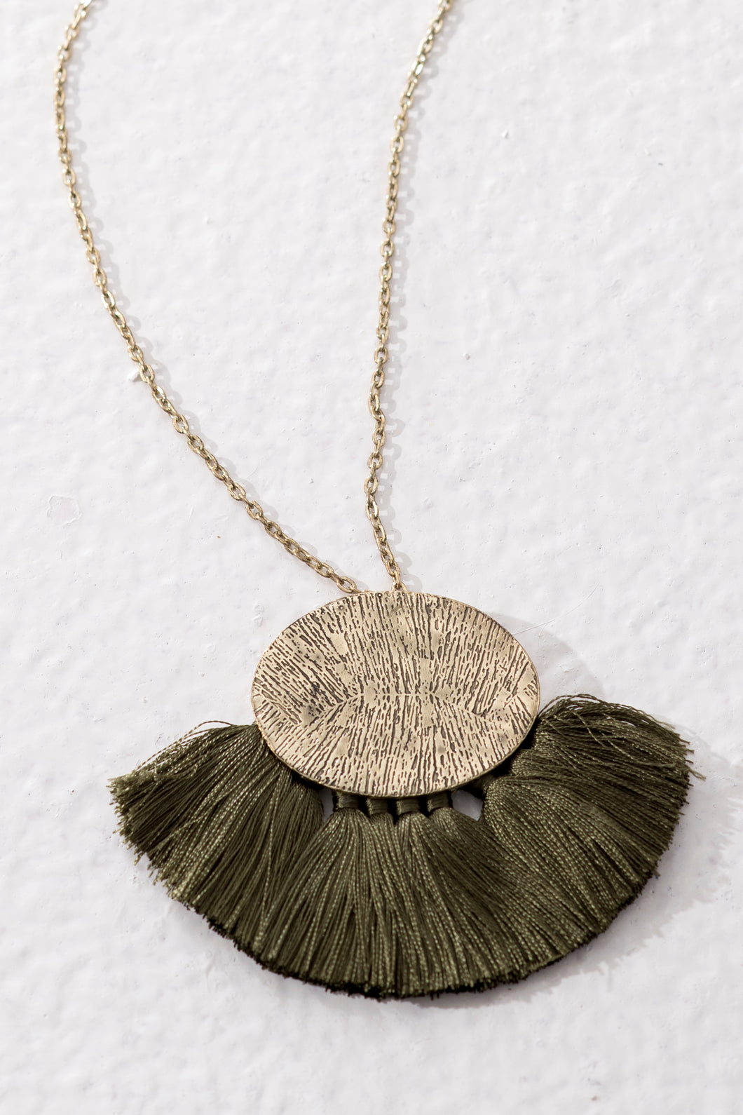 Handmade fair trade jewellery with long chain and textured golden brass pendant. Olive green tassels