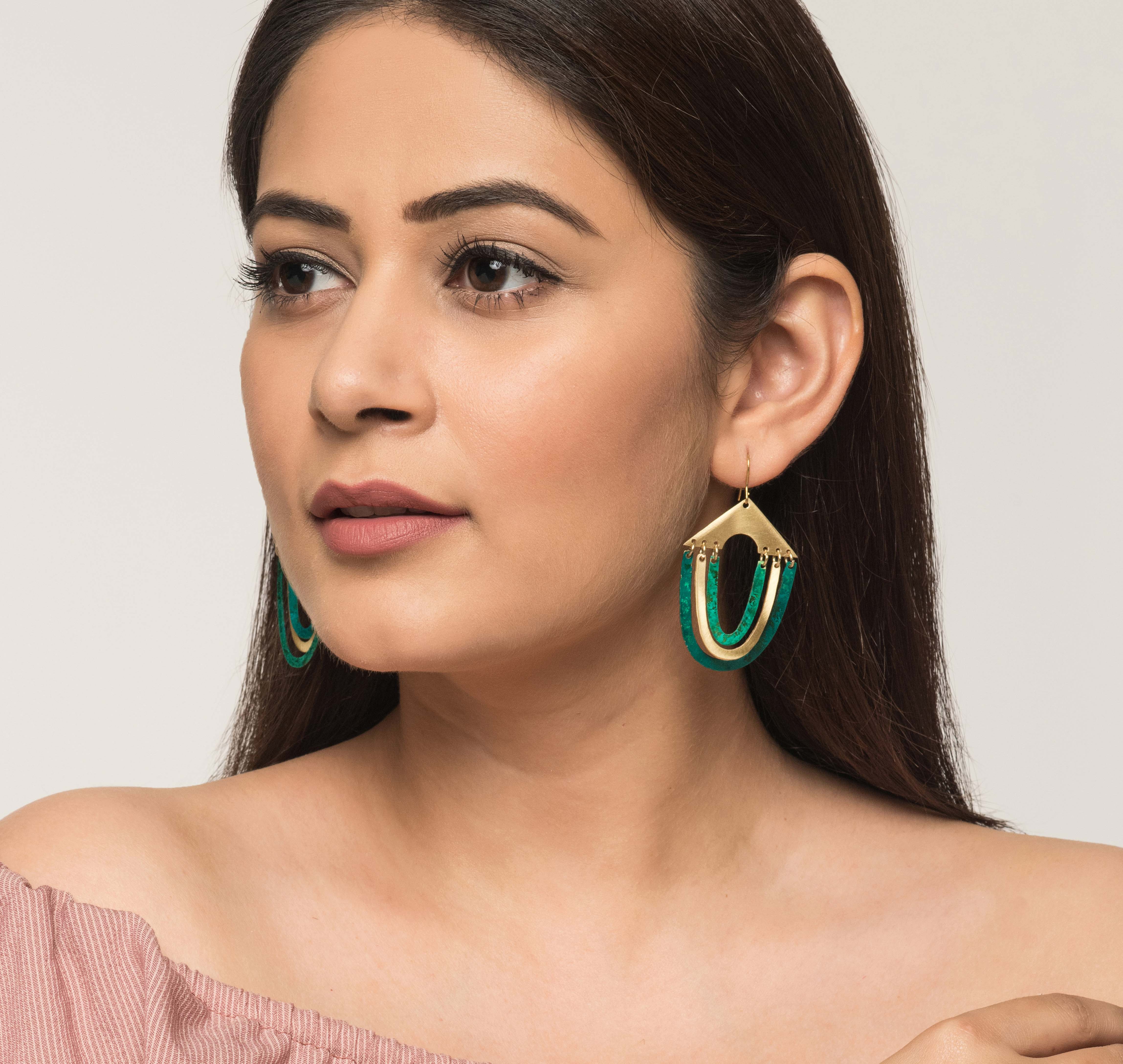 Woman wearing contemporary earrings. Green and golden brass fair trade jewellery. Handmade in India.