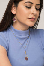Woman wearing reversible ethical jewellery. Earring and necklace set with purple and white sides. 
