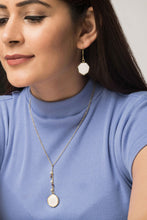 Woman wearing reversible ethical jewellery. White side of earrings and necklace. Also a purple side.
