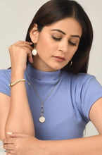 Woman wearing reversible ethical jewellery. White side of earrings and necklace. Also a purple side.