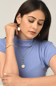 Woman wearing reversible ethical jewellery. White side of earrings and necklace. Also a purple side.