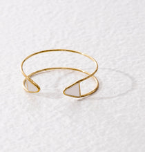 Open ended adjustable ethical bracelet made of golden brass and finished with white triangular tips.